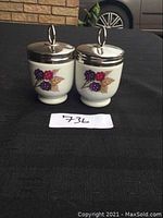 Photo showing two Royal Worcester egg coddlers with purple and red berry decoration and metal lids