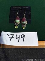 Front view of sterling silver earrings with bloodstone and peridot on black card labeled Sterling Silver.