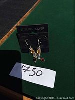 Pair of sterling silver multi-gemstone dangle earrings on black display card labeled 'STERLING SILVER'. Earrings feature amethyst, garnet, citrine, and labradorite stones. Price tag '750' shown in front.