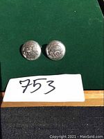 Front view of the two round sterling silver earrings showing the engraved floral pattern and polished finish.