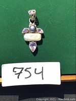 Front view of the sterling silver pendant featuring purple pearl, amethyst stones, and a stick pearl on a green background.