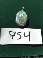 Front view of oval sterling silver locket with iridescent paua shell inlay on front surface.