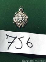 Front view of sterling silver pendant shaped like a sun with a face in the center, displaying detailed rays and facial features.