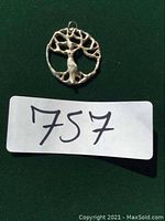 Photo of sterling silver 925 dryad tree pendant on green background, shows front side with detailed open tree design and loop for chain.