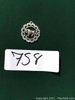 Close-up front view of a round sterling silver Taurus astrological pendant on a dark background with lot number shown.