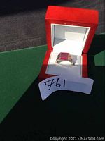 Top-down view of ring in red presentation box showing ruby and band