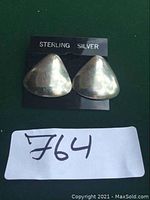 Front view of the pair of sterling silver triangular-shaped post earrings on a black backing card labeled 'STERLING SILVER'.