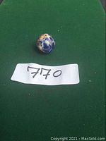 Photo showing the polished lapis lazuli sphere on a green background with label 770