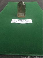 Smoky quartz ghost crystal point standing upright on green felt background with lot number tag.