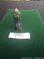 Front and side views of a labradorite crystal point about 3 inches tall placed on a green mat with lot number 775.