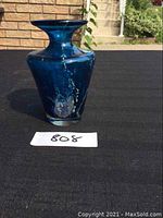 Front view of cobalt blue glass vase with flared rim on black cloth surface.