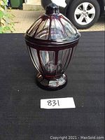 Front view of the deep ruby and clear blown glass candy dish with cover sitting on a black surface.