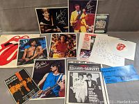 Collection of autographed photos, postcards, tickets, newspaper insert, and memorabilia scattered on a table