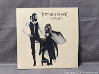 Front cover of Fleetwood Mac Rumours vinyl LP album, cream background with black and white band member image, title and artist name visible.