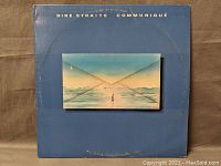 Front cover of Dire Straits Communiqué vinyl LP showing blue background with envelope artwork.
