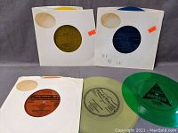 Five flexi discs in white paper sleeves with colored label centers visible, arranged in a group view