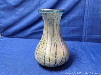 Front view of the iridescent glass vase, showing elongated neck and bulbous base with vertical decorative lines and yellow dot accents.