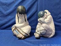 Front view of both figurines side by side on blue backdrop