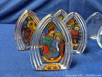 Five colored Wedgwood Christmas paperweights showing stained glass window scenes with vibrant colors.