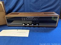 Front view of Strauss Model LT 170 radio with wood grain top, black front panel with tuning scale and control knobs, shows new old stock condition.