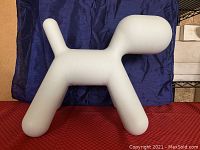 Top view showing the sculpture's head, body, tail, and legs placed on red and blue fabric backgrounds.