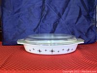 Front view of the Pyrex divided casserole dish with clear glass lid showing the Compass pattern on the side.