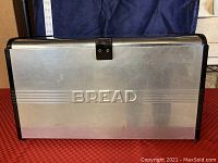 Front view of vintage mid-century Kromex aluminum bread box embossed with 'BREAD'.