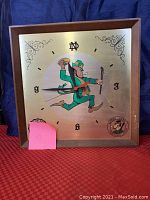 Front view of the square Notre Dame football clock with caricature artwork and clock hands.
