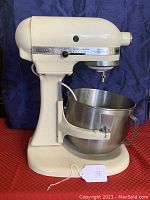 Front side view of the off-white KitchenAid K5SS stand mixer showing stainless steel bowl and speed control lever.