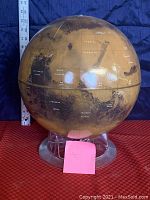 Side view of Mars globe on original clear display stand with yardstick for size reference, showing labeled planetary features