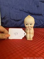 Frontal view of the Kewpie doll figurine showing sitting pose and light discoloration on head's tuft area.