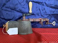 Side view of antique German Harras cast iron food mill grater showing wooden handle on crank and heart-shaped clamp.