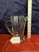 Front-side view of the etched glass pitcher next to a measuring scale showing about 9 inches in height. Visible shooting stars design is etched around the body.