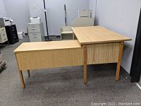Side view of the L-shaped corner desk showing main desk surface and attached extension piece.