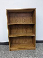 Front view of brown 3 shelf wooden unit showing three shelves and wood grain.