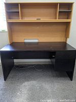 Full view of the dark desk with the light brown attached back showing drawers and shelf compartments