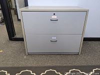 Front view of grey metal lateral file cabinet with two drawers, showing closed drawers and lock at top drawer.