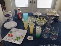 Full overview of all items including glasses, tumblers, serving dishes, plates, reusable bottles on a blue tablecloth.