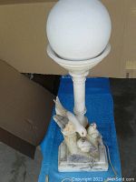 Full view of the alabaster carved lamp with bird design on marble base and white glass globe.