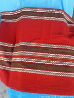 Red woven fabric featuring brown and white horizontal stripes, part of a small mat