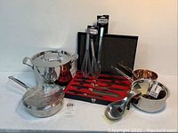 Full view of Todd English knife set in black case with red interior, displayed alongside Cuisinart cookware including stockpot, saucepan, sauté pan, and kitchen accessories on a counter.