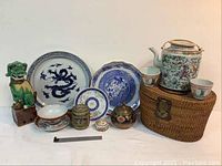 Overall view of tea set, plates, foo dog, brass containers, hex box, and wicker basket