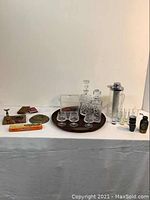 Full display of all items including decanters, glasses, icebox, cocktail server, ashtrays, dominoes, and playing cards on a white tablecloth.