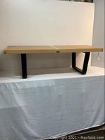 Full view of bench showing natural maple slatted top and ebony legs