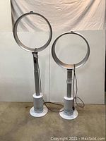 Two Dyson bladeless air multiplier fans side by side, one with rod extended and one collapsed.
