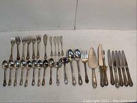 Overall layout of all 33 pieces showing forks, knives, spoons and serving utensils