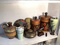 Wide view showing all items in the lot including vases, pottery jug, wooden canisters, masks, and other decor