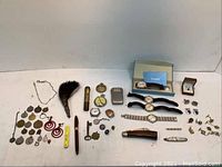 Full overview of vintage men's accessories lot, showing all included items spread on a white surface, including watches, medallions, earrings, cufflinks, cutters, and pen.
