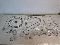 Full lot of over 20 sterling silver jewelry items displayed on flat surface including various chains, bracelets, earrings in bags, and a pendant.