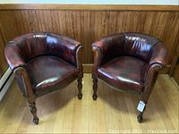 Pair of leather armchairs side by side against wood paneled wall